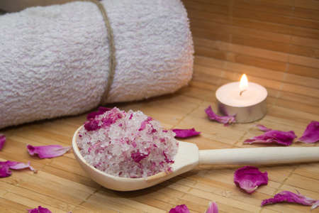 homemade body scrub from sea salt and rose petals and peony candle,pink towel on a straw Mat. Spa conceptの写真素材