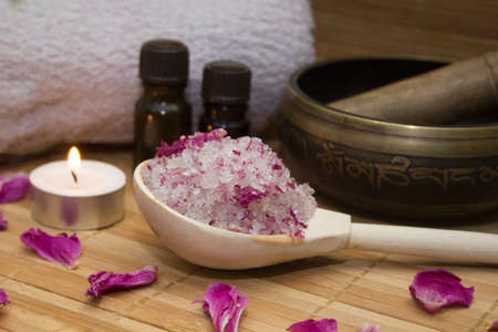 homemade body scrub from sea salt and rose petals and peony, Tibetan bowl,candle,pink towel and aroma oil  on a straw Mat. Spa conceptの写真素材
