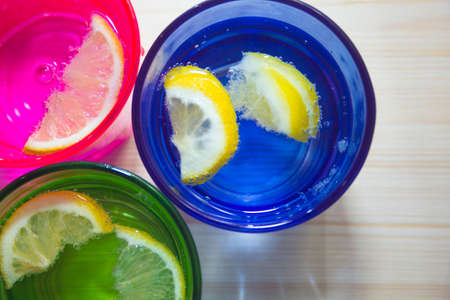 Sparkling water, soda or a gin and tonic in colorful glasses with lemon and ice.Concept for bar menu or detox  with water with lemon.の写真素材
