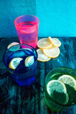 Sparkling water, soda or a gin and tonic in colorful glasses with lemon and ice.Concept for bar menu or detox  with water with lemon.の写真素材