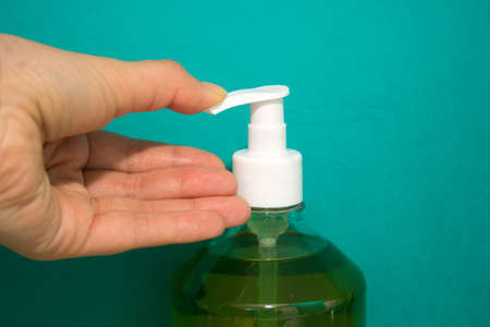 Hand presses on the dispenser for liquid soap or other cleaning product.の写真素材
