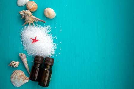 Spa concept. Seashells , aroma oils and  sea salt  on blue wooden backgroundの写真素材