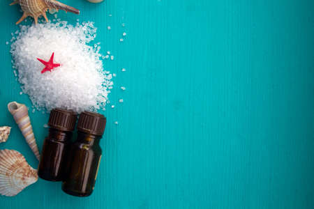 Spa concept. Seashells , aroma oils and  sea salt  on blue wooden backgroundの写真素材