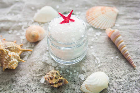 Seashells and a jar of sea salt on a grey cloth background. Spa concept.の写真素材