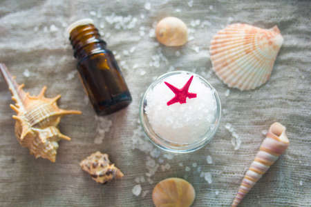 Shell, aromatherapy oil and a jar of sea salt on a grey cloth background. Spa conceptの写真素材