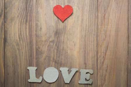 background with a heart and the words love on wooden tableの写真素材