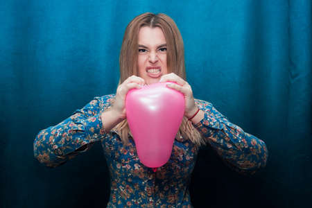 angry young white girl in a denim shirt burst heart shaped balloonの写真素材