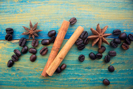 coffee beans, cinnamon sticks and star anise on wooden background painted in blue and gold. place for text.の写真素材