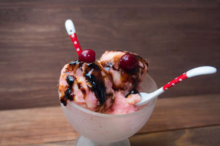 fruit ice cream served with cherries and chocolate syrupの写真素材