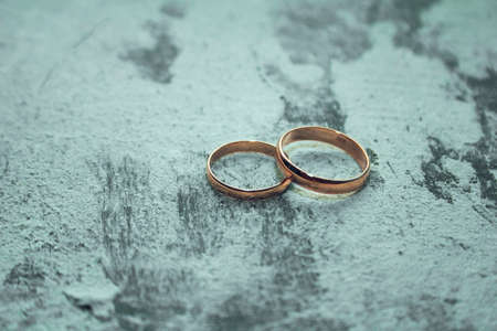 gold wedding rings on the rough plaster backgroundの写真素材