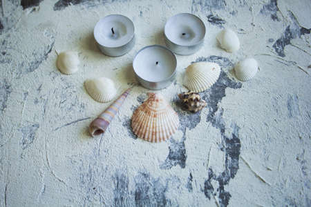 Spa concept: seashells and candles on the rough plaster backgroundの写真素材