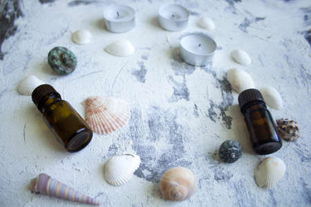 Spa concept: seashells, candles and aroma oils on the rough plaster background