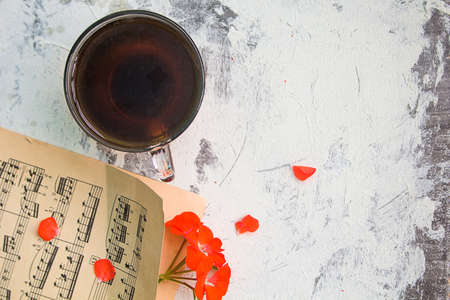 morning coffee, music sheets and a red flower