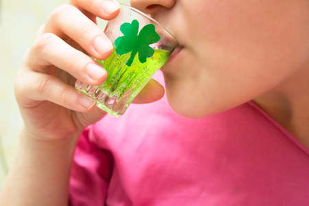 woman drinks an alcoholic shot on St. Patrick's dayの写真素材