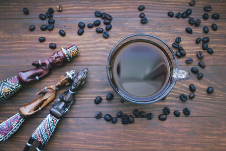 coffee Cup, coffee beans and wooden African statues. the concept of traveling to Africaの写真素材