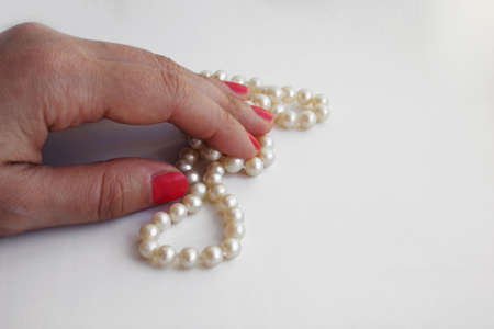 Female hand holds a pearl bead on a white backgroundの写真素材