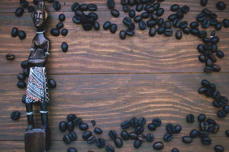 wooden background with African statuette and frame made from coffee beans.の写真素材