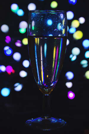 a glass of sparkling wine on the background of colored lightsの写真素材