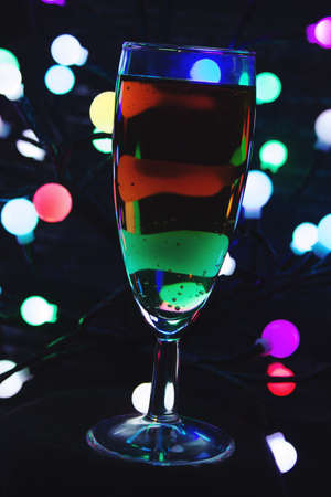 a glass of sparkling wine on the background of colored lightsの写真素材
