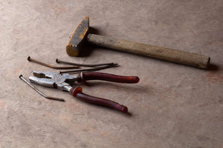 rusty old nails ,hammer and pliers on wooden background
