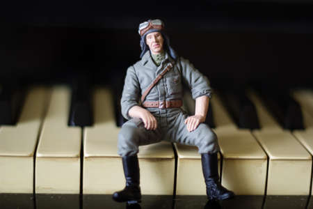 toy military man sits on the keys of a pianoの写真素材