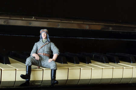 toy military man sits on the keys of a pianoの写真素材