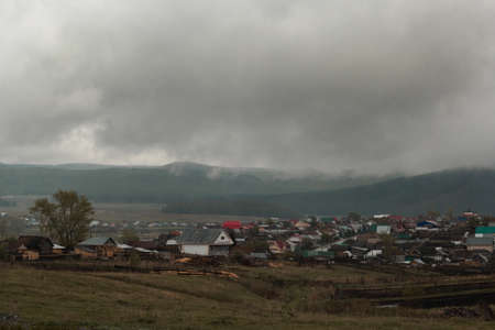 beautiful rural landscape with the village and the Ural mountains in the fogの写真素材