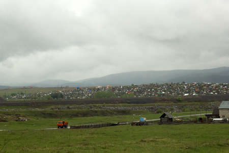 beautiful rural landscape with the village and the Ural mountains in the fog.の写真素材
