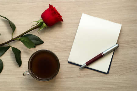 rose, cup of coffee, pen and white blank sheet on the table, top viewの写真素材