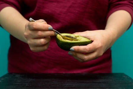 woman use a spoon to scoop the avocado out of the shellの写真素材