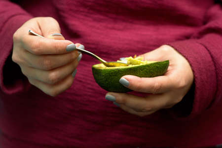 woman use a spoon to scoop the avocado out of the shellの写真素材