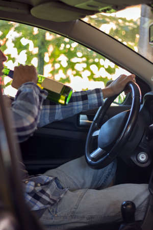 Young man drinking beer while driving. the problem of alcoholism and drunk driving.の写真素材