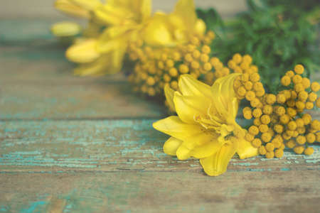 yellow mimosa and  lily flowers on the old weathered tableの写真素材