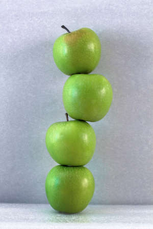 stack of green apples on grey background. the concept of balancehealthy lifestyle and team workの写真素材