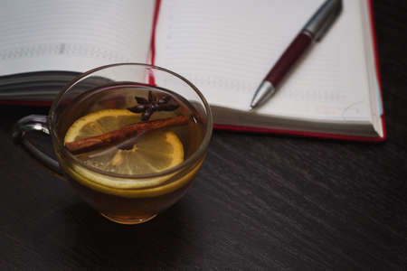 diary, pen and warming tea with lemon and spicesの写真素材