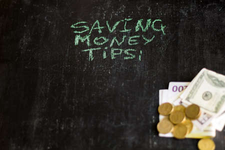 saving money tips inscription on chalk board and blurred money.の写真素材