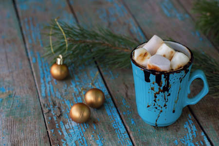 warming hot cocoa with marshmallows in a blue mug on the rustic table among the Christmas decorationsの写真素材