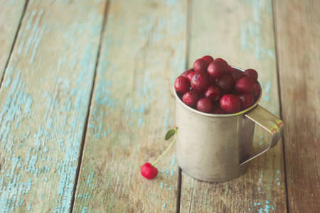 fresh cherries in a metal cup on the tableの写真素材