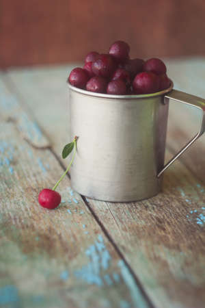 fresh cherries in a metal cup on the tableの写真素材