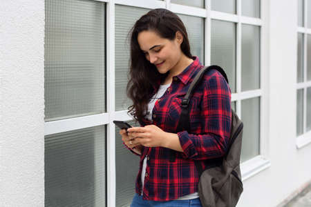 young girl student in a campus uses a mobile phoneの写真素材