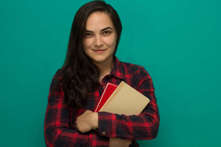 young girl student in a red plaid shirt with booksの写真素材