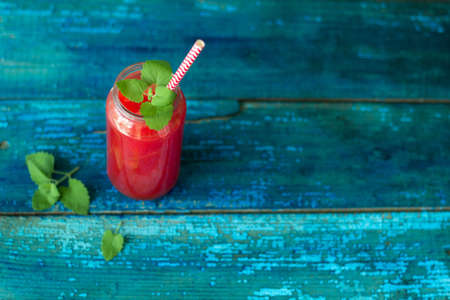 resh watermelon juice with mint in a jar with a straw on a blue wooden table