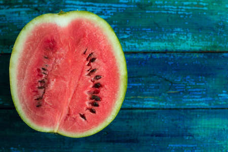 half of  watermelon on a bright blue wooden backgroundの写真素材