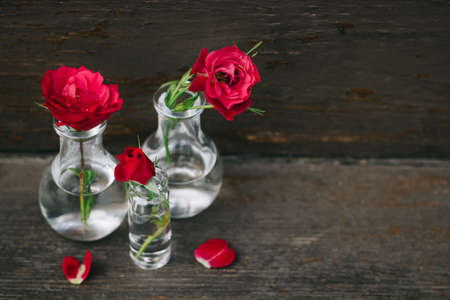Red roses in a small vintage vases on a brown backgroundの写真素材