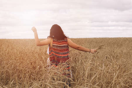 a young girl in a field of wheat. warm solar toning