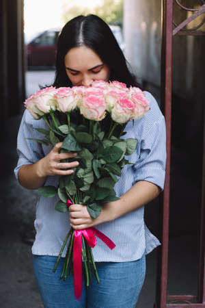 girl holding a bouquet of pink roses and enjoy their aroma with her  eyes closedの写真素材
