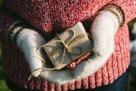 girl hands in white woollen mittens holding a gift boxの写真素材