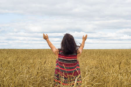 young brunette girl standing on wheat field and enjoying natureの写真素材