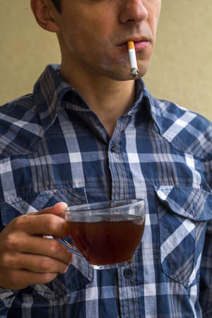 young man with a ?up of black coffee and a cigaretteの写真素材