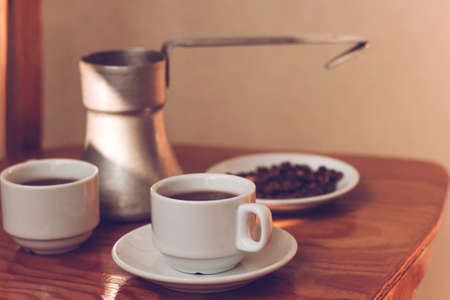 two cups of black coffee and cezve  on the tableの写真素材